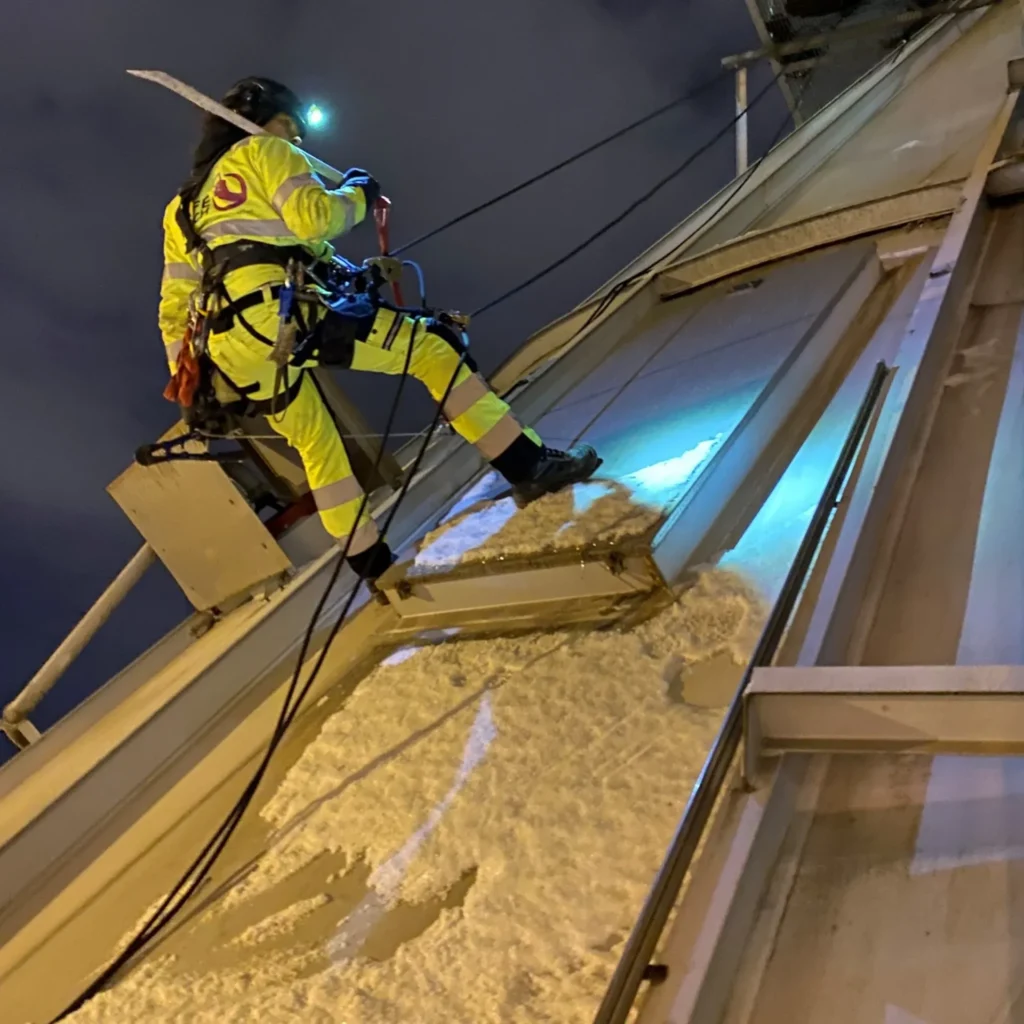 En kvinna klättrar via industriklättring.