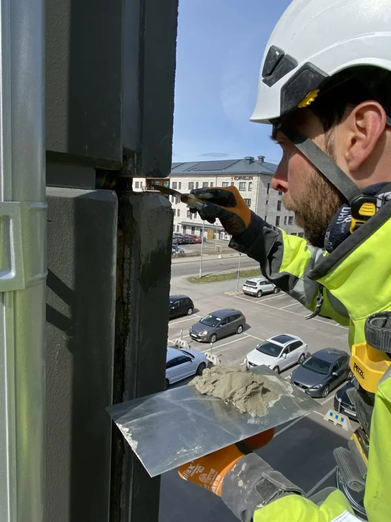 En man arbetar med betongrenovering som en industriklättrare.