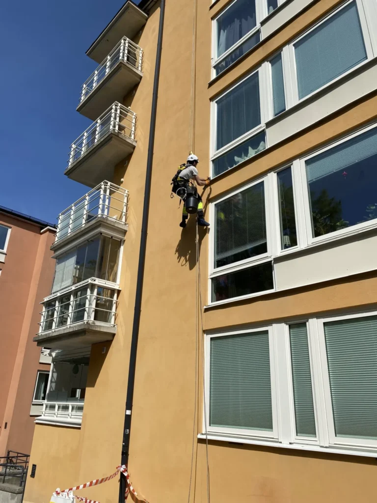 Rope Access klättrare utför fasadreparation i Stockholm.