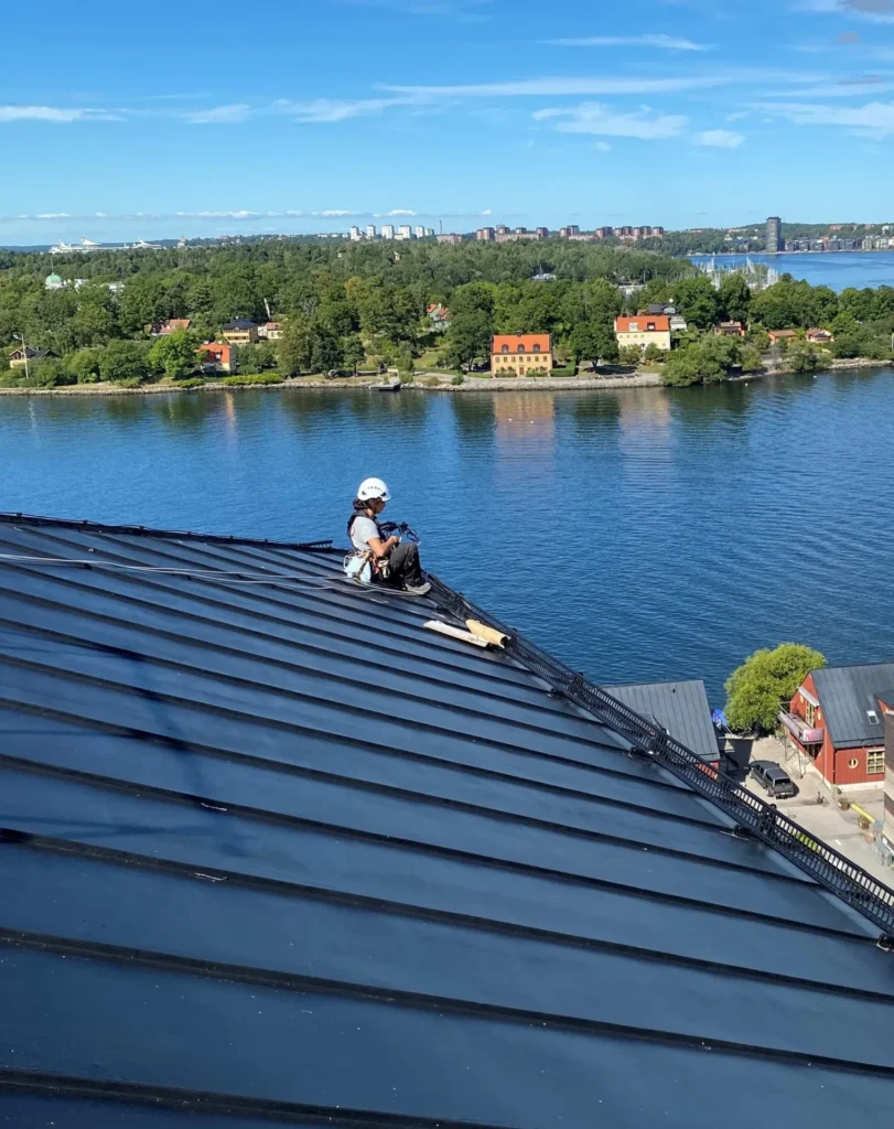 Ett tak i plåt med en reparbetare som blickar ut över Östersjön.