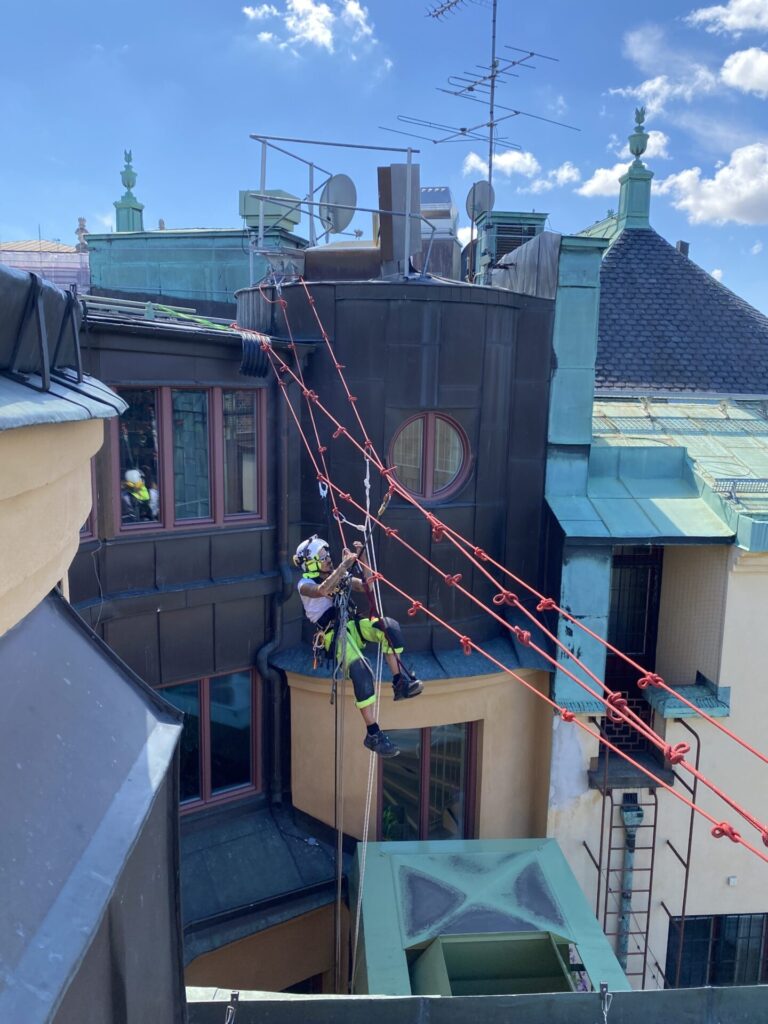 En Rope Access klättrare hänger över en innergård.